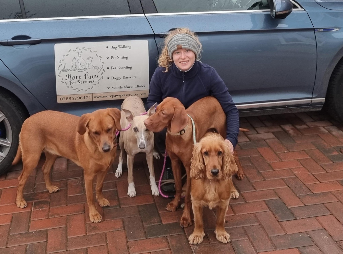 Lucy with four dogs in front of her car